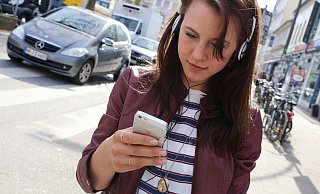Ein weiblicher Smombie mit Kopfhörer. Der Blick aufs Handy, die Ohren mit Musik beschallt. So ist man im Straßenverkehr besonders in Gefahr. - Symbolfoto: picture alliance / dpa