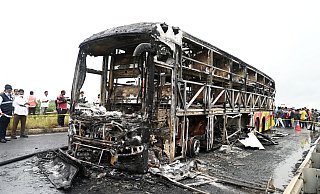 Die verkohlten Überreste des Passagierbusses liegen auf einer Landstraße im Dorf Chinnatekuru. - -/AP/dpa