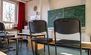 Hochgestellte Stühle in einem leeren Klassenzimmer einer Gesamtschule. - Foto: Guido Kirchner/dpa