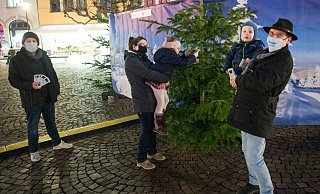 Dana Zettel hilft Tochter Lucy dabei, ihren Pinguin in die Zweige zu hängen, ihr Bruder Lucas schaut zu. Schausteller Björn Laffontien (l.) und Stadtführer Mathias Polster bitten um Spenden für den großen Baum auf dem Alten Markt. - Ralf Bittner