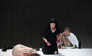 Beäugt von einem speisenden, namenlosen, dickleibigen Gott (Jörg Lemm) hat die verzweifelte Iphigénie (Melanie Kreuter) wieder einen Menschen (Jens Walsermann) geopfert. - FOTO: MATTHIAS STUTTE