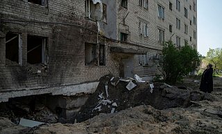 Eine Frau neben dem Krater einer Explosion, die in Lyman eine Wohnung und einen Keller eines Wohnhauses beschädigt hat. - Foto: Leo Correa/AP/dpa
