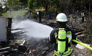Von dem Hühnerstall an der Haller Straße blieb nur noch ein Gerippe stehen. Ein Feuerwehrmann löscht die letzten Glutnester in den Trümmern.  - Andreas Eickhoff
