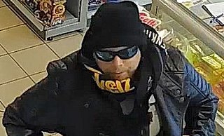 Das Bild zeigt den dringend Tatverdächtigen mit dem Messer in der Hand in der Tankstelle. - Polizei Herford