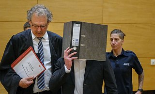 Der 21-jährige Mörder hält einen Aktenordner vor sein Gesicht. Sein Verteidiger, Georg Schulze, begleitet ihn am Bielefelder Landgericht. - Andreas Zobe