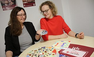 „Auf Augenhöhe“-Projektleiterin Carolin Schnückel (l.) und SkF-Chefin Daniela Dahlmann schauen nach den Mosaiksteinen, die als Youngcaritas-Projekt in der Laurentius-Schule entstanden und jetzt vor den bunten „Bänken für Toleranz“ in der Stadt verlegt werden sollen. - Dieter Scholz