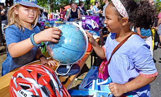 Erinnerungen an den Flohmarkt 2022: Paul Washner (9) hat sein Kinderzimmer entrümpelt und ist mit seinen Eltern zum Flohmarkt gekommen. Anissa (8) aus Stieghorst ist ganz angetan von dem Globus. - Barbara Franke
