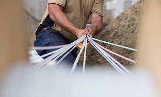 Ein Techniker verlegt Glasfaserkabel in einem Wohngebiet – eine Investition in die Zukunft des schnellen Internets. - picture alliance/dpa