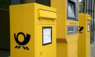 Gelber Briefkaesten mit Posthorn und gelber Briefmarkenautomat am Eingang einer Postfiliale in Freiburg am 03.05.2015.Foto: Winfried Rothermel | Verwendung weltweit - Verwendung weltweit