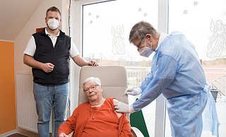 Marianne Drews ist mit 86 Jahren die erste Bewohnerin des St.-Johannes-Seniorenhauses der KHWE, die von Rüdiger Micus gegen das Corona-Virus geimpft wird. Einrichtungsleiter Oliver Surmann kümmert sich an diesem Tag um den reibungslosen Ablauf vor Ort. - KHWE