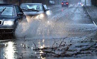 Autos fahren langsam durch eine tiefe Pfütze die sich durch Starkregen gebildet hat. - picture alliance/dpa