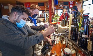 Den Zapfhahn fest im Griff: Amir Nemat (vorne) und Max Meis haben alle Hände voll zu tun. Das Schankbier fließt in verschließbare Flaschen. Die Kundschaft hinter dem Tresen wartet. - Sarah Jonek