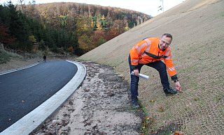 Tobias Fischer vom Landesbetrieb Straßen.NRW zupft am Sisal-Netz, das bis fast zur Kuppe des Hügels reicht. Es stabilisiert die abgeflachte Böschung und schützt die sprießenden Gräser. - Dieter Asbrock