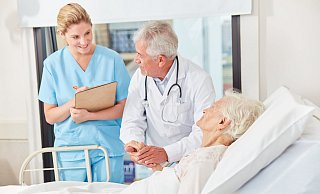 Visite: Arzt und Krankenschwester stehen in einer Klinik am Bett einer Patientin. - picture alliance / Zoonar