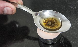 Tödliche Droge: Das Archivbild zeigt, wie ein Mann in einem Löffel einen Schuss Heroin vorbereitet. Mit der Droge sollen die gefassten Männer unter anderem gehandelt haben. - dpa