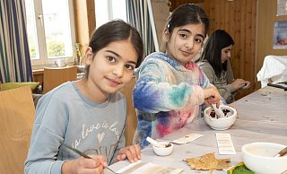 Sania (l., 8) und ihre Schwester Sandra (10) finden die Farben richtig cool - Sandra zermörsert Rosenblätter, Sania malt schon mit gefärbtem Wasser. - Jörg Dieckmann