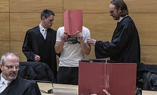 Prozessstart: Zwei der Angeklagten halten sich Schnellhefter vor das Gesicht. Neben ihrem Mandanten, einem der beiden Hauptangeklagten, in der zweiten Reihe stehen die Strafverteidiger Mario Prigge (l.) und Sven Peters (r.). Vorne sitzen Rechtsanwalt Peter Jahn. Seinem Mandanten wird Beihilfe vorgeworfen. - Jörg Dieckmann Prozessstart: Zwei der Angeklagten halten sich Schnellhefter vor das Gesicht. Neben ihrem Mandanten, einem der beiden Hauptangeklagten, in der zweiten Reihe stehen die Strafverteidiger Mario Prigge (l.) und Sven Peters (r.). Vorne sitzen Rechtsanwalt Peter Jahn. Seinem Mandanten wird Beihilfe vorgeworfen. - Jörg Dieckmann