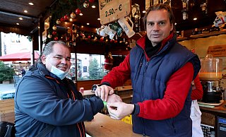 Kunde Jürgen Feyerabend lässt sich das grüne Bändchen von Schausteller Raoul Krameyer gerne anlegen. - Frank-Michael Kiel-Steinkamp