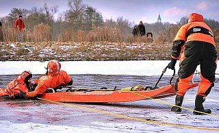 Dennis Streitbürger (rechts) hält den Schlitten, Philipp Lemmen zieht Bernd Dieske aus dem See. Er hatte sich für die Feuerwehr-Übung in den eiskalten Johannisbach gestürzt. Einige Spaziergänger schauten zu .
