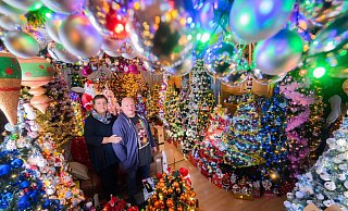 Mehr Weihnachten geht kaum: Susanne und Thomas Jeromin stehen inmitten von Weihnachtsbäumen im Wohnzimmer ihres Hauses. - Julian Stratenschulte/dpa
