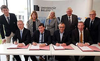 Wichtige Unterschrift: Rainer Norden (Aufsichtsratsvorsitzender des evangelischen Klinikums Bethel, vorne v. l.), Michael Ackermann (Geschäftsführer Klinikum Bielefeld), Gerhard Sagerer (Rektor der Universität Bielefeld) und Johannes Hütte (Geschäftsführer Klinikum Lippe) unterzeichnen die Kooperationsvereinbarung für das Universitätsklinikum OWL. Frank Lohkamp (Geschäftsführer der medizinischen Fakultät, hinten v. l.), Claudia Hornberg (Gründungsdekanin), Isabel Pfeiffer-Poensgen (NRW-Wissenschaftsministerin), Karl-Josef Laumann (NRW-Gesundheitsminister) und Stephan Becker (Kanzler der Universität Bielefeld) schauen ihnen dabei zu. - Wolfgang Rudolf