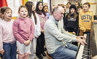 "Hey, hallo, bonjour, guten Tag", singen die Kinder. Thorsten von Petersen-von Knebel begleitet sie am Flügel. - Jörg Dieckmann