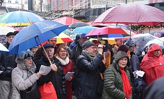 Mit bunten Regenschirmen schützen sich die Menschen auf dem Marktplatz vor dem Regen. Gesungen wird trotzdem fleißig. - Thomas Kube