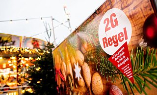 Ein Schild mit der Aufschrift "2G Regel" am Eingang eines Weihnachtsmarkts. - Foto: Hauke-Christian Dittrich/dpa