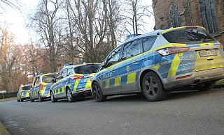 Vier Einsatzwagen der Polizei parken auf einer Zufahrt zum Parkplatz der Pauluskirche in Bünde. - Jan-Henrik Gerdener