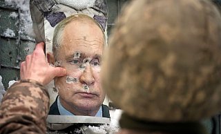 Ein ukrainischer Soldat justiert ein von Kugeln durchlöchertes Bild des russischen Präsidenten Putin. - Foto: Vadim Ghirda/AP/dpa