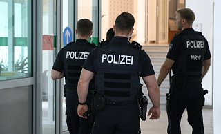 Drei Polizisten führen den Zeugen aus dem Gerichtsgebäude, nachdem er den Angeklagten im Gerichtssaal mit dem Tode bedroht hat. - Claus Frickemeier