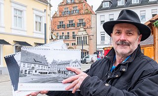 Mathias Polster zeigt den Kalender "Herforder Ansichten 2025" auf dem Neuen Markt. Der ist auch im Kalender zu sehen, allerdings noch mit Autoverkehr. - Ralf Bittner
