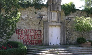 Ein rotes Graffiti und die mit Tapetenbahnen überklebte Gedenktafel des Mahnmals am Paderborner Busdorfwall. - Marc Schröder