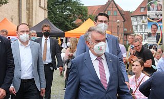 Der NRW-Innenminister, Herbert Reul (Mitte), schreitet mit NRW-Maske und seinen Gastgebern Tim Ostermann (l., Mitglied im Bundestag) und Joachim Ebmeyer (r., Bundestagskandidat) über den Münsterkirchplatz. - Susanne Barth