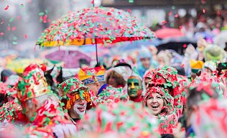 Karnevalisten sind komplett mit nassem Konfetti bedeckt und feiern die Eröffnung des Straßenkarnevals in Köln. - Rolf Vennenbernd/dpa