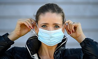 Eine Frau in Herford zieht ihre Gesichtsmaske auf, um sich vor dem neuen Coronavirus zu schützen. - picture alliance / Eibner-Pressefoto