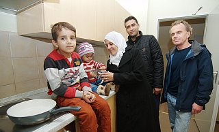 Angekommen: Die syrische Familie Barisho freut sich über die Unterkunft. Sozialarbeiter Rolf Linnemann (r.) und Helfer übergeben gespendete Pakete mit Küchenutensilien an die Flüchtlinge. - thom