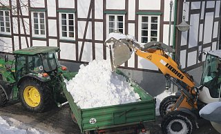 Ein Radlader lädt in Enger an der Burgstraße/Ecke Mathildenstraße Schnee auf einen Traktorenanhänger. - Ekkehard Wind