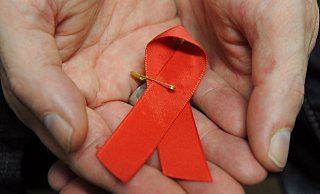 Ein mit dem HI-Virus infizierter Mann mit einer roten Schleife als Symbol der Solidarität mit HIV-Positiven und Aids-Kranken. - Arne Dedert/dpa
