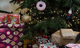 Eingepackte Geschenke liegen unter einem geschmückten Weihnachtsbaum. Die Menschen in Deutschland wollen in diesem Jahr bei den Präsenten sparsamer sein. - Swen Pförtner/dpa