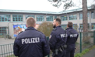Drei Polizisten haben am Mittwochmittag die Grunschüle Bünde-Mitte im Blick. - Florian Weyand