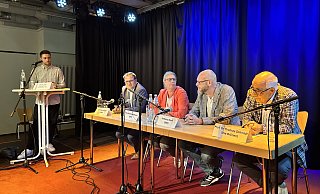 Moderator Denis Utas und die Bürgermeisterkandidatin und -kandidaten auf dem Podium in der Druckerei. - Nicole Sielermann