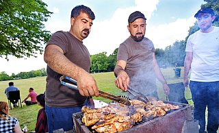 Khaled Kassem (Mitte) hat jede Menge Hähnchenfleisch auf den Grill gelegt. Beim Treffen mit der Großfamilie auf dem öffentlichen Platz an den Heeper Fichten an diesem Sonntag gedenkt er auch seiner kürzlich im Irak verstorbenen Mutter. - Barbara Franke