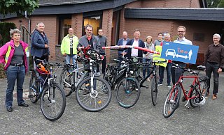 Gut ein Dutzend Interessierte treffen sich in der Versöhnungskirche, um über das Radfahren in SHS zu sprechen. Der ADFC-Vorstand, Daniel Neuhaus und Fritz Spratte, weist mit einem Schild und einem Polyethylenschaumstab auf den Überholabstand von 1,50 Meter hin. - Sigurd Gringel