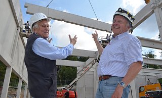 Wolfgang Soldan, ehemaliger Leiter des Betonfertigteilwerks Bielefeld (l.), und Bauleiter Achim Bokermann beobachten, wie eine Strebe für das Dach der Sporthalle heranschwebt. Foto: Sibylle Kemna - Sibylle Kemna