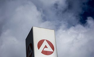 Wolken ziehen über ein Schild der Agentur für Arbeit und dem Berlin-Lichtenberg. - Foto: Carsten Koall/dpa
