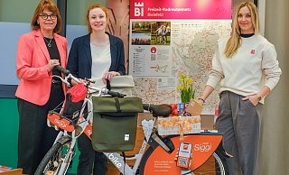 Gabi Lamm (v.l.), Jill Turner und Maya Regtmeier zeigen ein "Siggi-Rad" von Mobiel, den neuen Bielefeld-Rucksack und stellen das Programm vor. - Andreas Zobe