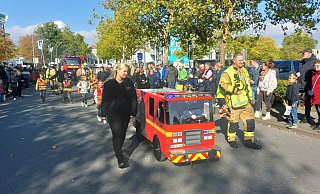Im Festzug: Das Mini-Feuerwehrauto steuern Leni und Phil, die Eltern Janine und Maik Menne sichern links und rechts ab. - Dieter Scholz