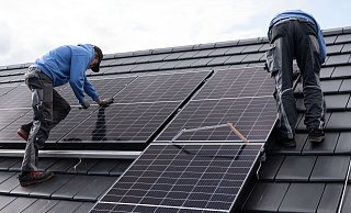 Handwerker montieren Fotovoltaikmodule auf dem Dach eines Wohnhauses. Bei neuen Anlagen gibt es ab Februar 2025 eine wichtige Änderung. - picture alliance/dpa