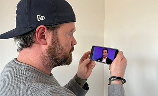 Kriminalhauptkommissar Thomas Konrad sieht sich auf seinem Handy das Motiv aus einem Deepfake-Video mit dem Antlitz von Elon Musk an. - Jan Schillmann